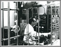 Technician measuring in NBS MW lab, around 1969.  His right hand is on a variac which controls the squarewave amplitude for Stark modulation.  The signal on the scope looks like 1st order Stark lobes (up) and zero field absorption (down). His left hand is on radio receiver tuned to 80 kHz.