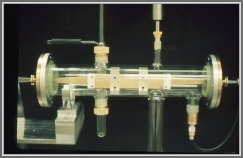 The millimeter wave parallel plate Stark cell used at frequencies from 40 GHz to  GHz, and in measurements including those on ClO, BrO, SF2, H2CS, CH2NH, CH2, HOCl, ClNO3 and HOONO2.  The sample inlet port, top left and exit port bottom right, allowed sample to be flowed directly between the two electrodes.  The cell was constructed in 1969 and was made entirely of glass and gold-coated metal to minimize decomposition the radicals and transient species.  The quartz sample inlet tube allowed a microwave cavity (Evanson design) to be attached in order to make a microwave discharge in the flowing sample gas.