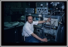 Stew Novick at the NBS FTMW spectrometer during sabbatical leave from Wesleyan University in 1988.  He is moving the Fabry Perot cavity mirror with the motor-mike control in his right hand and starting the TTL pulse sequence controlling the microwave switches and pulsed nozzle with the left hand, while enjoying unspecified audio.